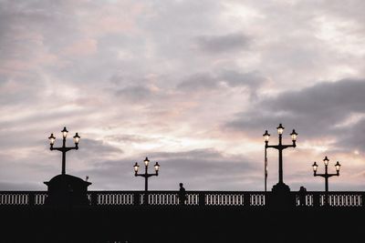 View of weather vane against cloudy sky