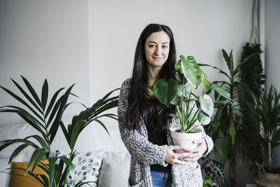 Portrait of smiling young woman with potted plants