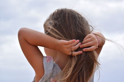 Portrait of woman with arms raised against sky