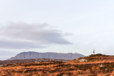 Distant view of woman standing on mountain