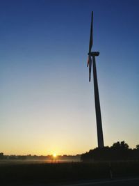 Low angle view of windmill on field against sky during sunset