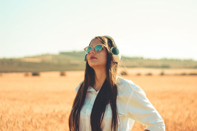 Portrait of young woman wearing sunglasses standing on field