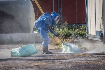 Full length of manual worker adding fertilizer on field