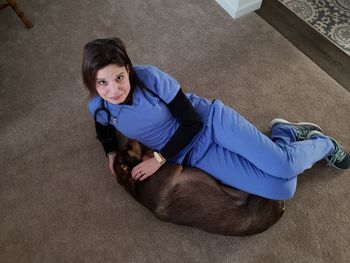 High angle portrait of woman lying with dog on floor