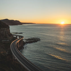 Bridge by sea against sky during sunset