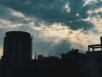 Low angle view of silhouette factory against sky