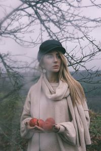 Young woman looking away while standing on tree