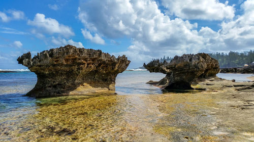 Rock formation on beach against sky