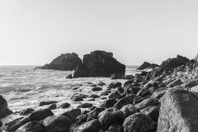 Scenic view of rocks on beach against clear sky