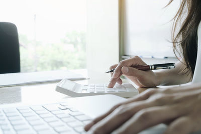 Midsection of woman using mobile phone on table