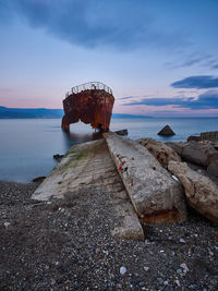 Wreck on shore at beach against sky