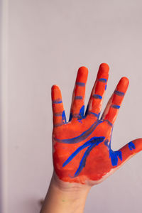 Red and blue, multi coloured child's painted hand up on the white background