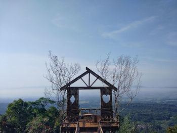 Traditional windmill on tree by building against sky