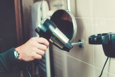Close-up of person holding hair dryer in bathroom