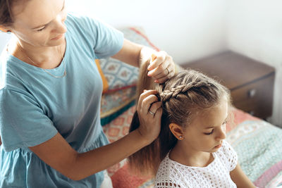 High angle view of mother hairstyling girl