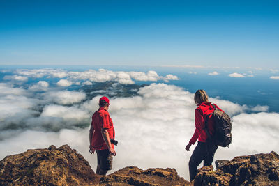 Rear view of people standing on rock against sky