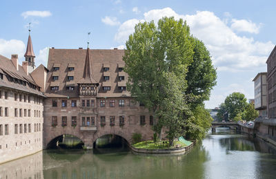 Arch bridge over river amidst buildings against sky