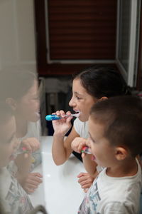 High angle view of siblings brushing teeth in bathroom