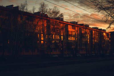 Road by building against sky during sunset