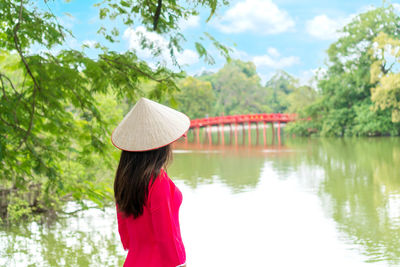 Rear view of woman standing by lake against sky