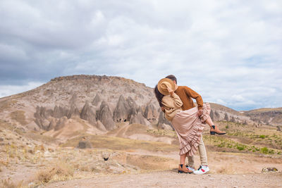 Young woman standing on mountain against sky