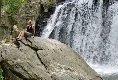 Man standing on rock formation in waterfall