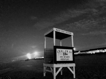 Information sign on beach against sky at night