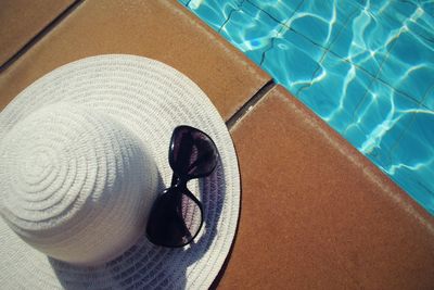 Overhead view of sun hat sunglasses on swimming pool