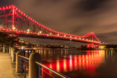 Illuminated bridge over river at night