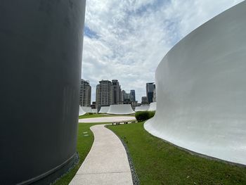 Footpath amidst buildings in city against sky