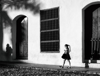 Full length of woman walking on street against building