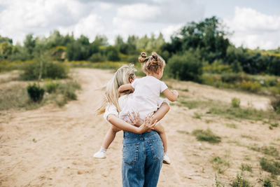 A happy mother and a little girl are playing together, a girl is riding on her mother's back