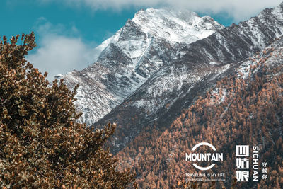 Information sign on snowcapped mountains against sky