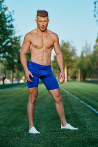 Portrait of shirtless man exercising on field