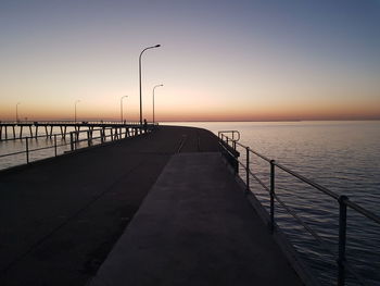 Pier on sea against clear sky during sunset