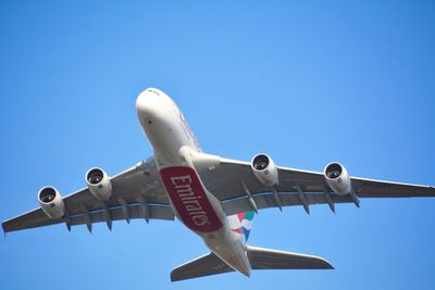 Low angle view of airplane against clear blue sky