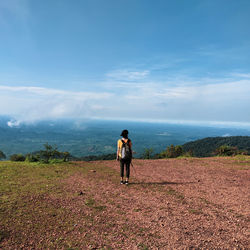 Rear view of woman walking on field against sky