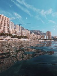 Sea by buildings against sky in city