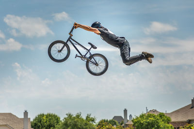 Low angle view of man performing stunt on bicycle against sky