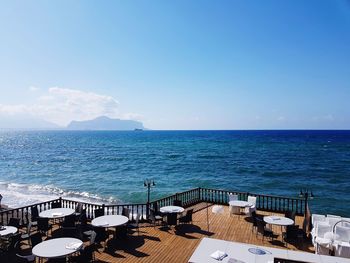 Empty restaurant by sea against blue sky