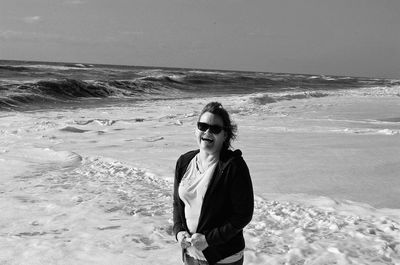 Scenic view of smiling woman standing in surf