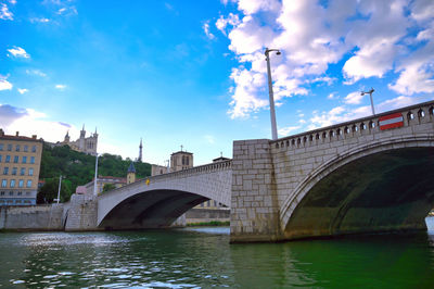 Arch bridge over river against sky in city