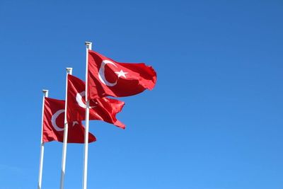 Low angle view of turkish flags against clear blue sky