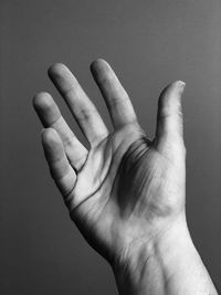 Cropped hand of man gesturing against gray background