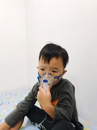 Boy with oxygen mask sitting on bed at home