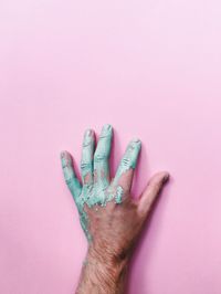 Cropped hand of man with messy paint on pink background