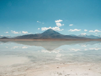 Scenic view of lake and mountains against blue sky