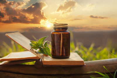 Close-up of glass jar on table against sky during sunset