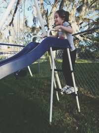 Full length of girl climbing on slide ladder at playground