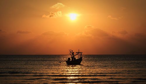 Silhouette boat sailing in sea against sky during sunset